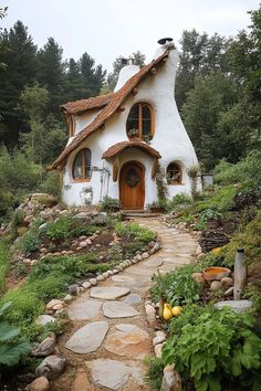 a small white house with a red door and windows on top of a hill in the woods