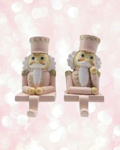 two small figurines sitting on top of each other in front of a pink background