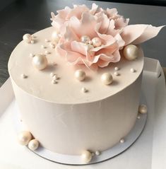 a white cake with pearls and a flower on top