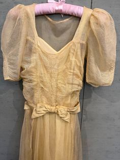 1930 vintage, Tea dress in pale yellow, silk tulle with it's, original, silk taffeta slip. The dress has a sweetheart neckline. The sheer puff sleeves have gathers down the middle to mirror the gathers in the front of the bodice. The belt is lined and has a bow in the front where it closes with 2 snaps. The skirt is double layer tulle over the silk taffeta slip. The two lengths of the fabrics in the skirt move beautifully at the hem line. There are 6 small repairs in the right sleeve and 5 in the skirts, total and all expertly done. Bust 32", waist 26", hips 34", bodice 18", skirt length 42". Can be hand washed in cool water and dry flat. The slip will need ironing, or, Dry clean Vintage Tea Dress, Silk Tulle, Yellow Silk, Silk Taffeta, Tulle Gown, Dress Yellow, Pale Yellow, Tea Dress, Vintage Tea