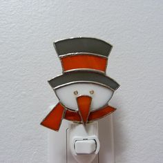 an orange and white light switch with a hat on it