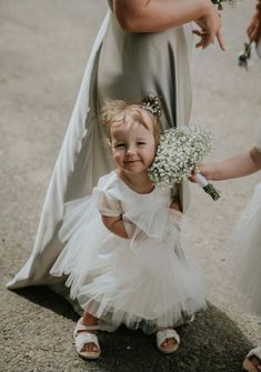 A beautiful handmade dress, perfect for flower girls, birthday, christenings, holy communion and any special occasions.  This dress is designed and handmade in our UK store (Worcester).  The dress is made from a soft duchess satin and has layers of soft tulle over the skirt. It features gorgeous puff tulle sleeves. It also has a ribbon bow sash, which you can customise to your colour preference.The perfect princess dress! The back has a cross over effect & has a zip fastening at the side. If you Baby In Wedding Dress, Ivory Girls Dress, Bow Sash, Flower Girl Dresses Tutu, First Communion Dress, Tulle Sleeves, White Flower Girl Dresses, Duchess Satin, Christening Dress