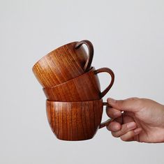 two wooden cups being held by someone's hand over the top of each other