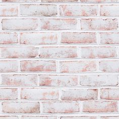 an old brick wall is painted white and has faded red paint on the top part