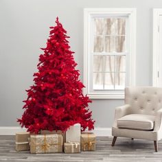 a red christmas tree sitting next to a chair