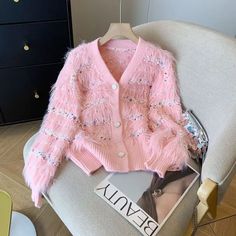 a pink sweater with sequins is sitting on a chair