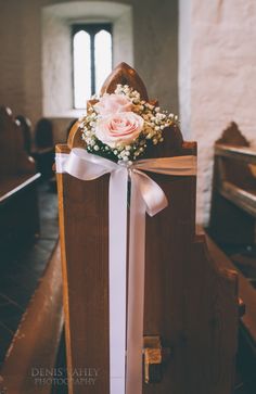 a bouquet of flowers sitting on the back of a church pew