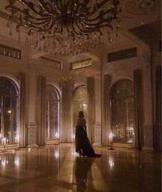 a woman standing in an ornate room with chandelier