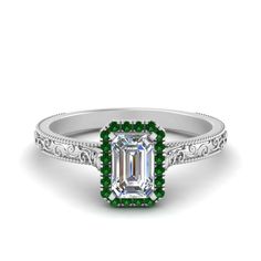 an emerald and diamond engagement ring with filigrees on the sides, set in white gold