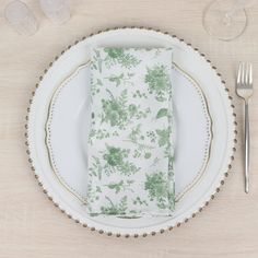 a white plate topped with a napkin next to a fork and knife on top of a wooden table