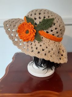 "This crochet beige floppy hat has open lace pattern with scalloped edge around the brim. It is accented with an orange flower and leaves. Hat measures 24\" in circumference (unstretched). It measures 5 1/2\" from top of crown to brim, Brim measures 4\" wide." Brown Crochet Hat For Spring, One Size, Brown Crochet Hat For Spring, One Size Fits Most, Spring Brown Crochet Hat One Size, Spring One Size Brown Crochet Hat, Adjustable Vintage Beige Crochet Hat, Vintage Adjustable Beige Crochet Hat, Brown Crochet Spring Hat, Adjustable Brown Crochet Hat For Spring, Spring Crochet Brimmed Hat With Crochet Trim