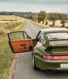 two cars are parked on the side of the road with their doors open and one is orange