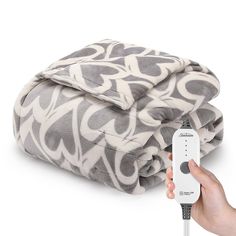 a person holding a remote control in front of a blanket on a white background with black and grey designs