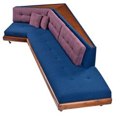 a blue couch with three pillows on it and a wooden arm rest in the middle