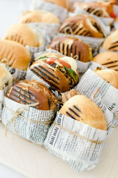 sandwiches wrapped in newspaper sitting on top of a table