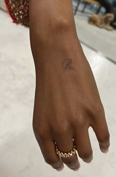 a woman's hand with a small tattoo on her left wrist and gold bracelet