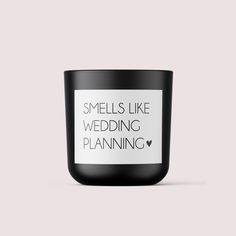 a black candle that says smells like wedding planning on the front and side, with white lettering