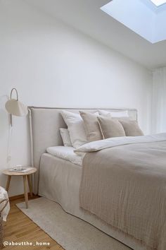 a bed sitting under a skylight in a bedroom next to a chair and table