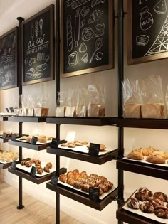 the bakery is stocked with breads and pastries for sale on shelves in front of chalkboard menus