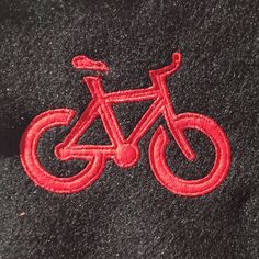 a close up of a red bicycle embroidered on a black jacket with a white background