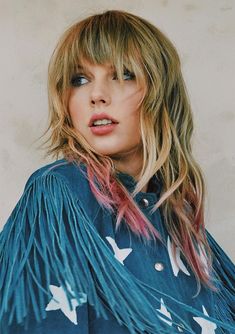 a woman with long blonde hair wearing a blue shirt and white birds on it's sleeves