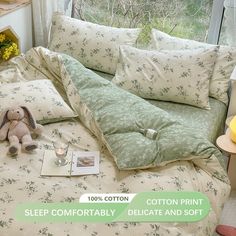 a bed with green and white comforter next to a stuffed animal on it's side