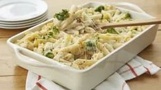 a casserole dish with broccoli and noodles in it on a wooden table