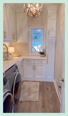 a washer and dryer in a small room with white cabinets, wood flooring and a chandelier hanging from the ceiling