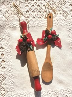 two wooden spoons with red bows and pine cones on them sitting next to each other