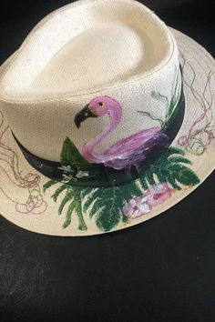 This is a totally hand painted straw hat, featuring a beautiful Flamingo in a totally natural environment, adding an exotic charm to your summer look. Each design is one of a  kind. Handmade Pink Straw Hat For Summer, Whimsical Pink Summer Hat, Handmade Pink Fedora For Spring, Artistic Hand Painted Summer Hats, Handmade Pink Sun Hat For Summer, White Artsy Summer Hat, Hand Painted Straw Hat For Beach Summer, Hand Painted Curved Brim Straw Hat For Summer, Artsy White Summer Hat