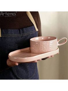 a person holding a pink cup and saucer