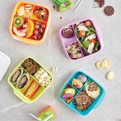 four plastic containers filled with food on top of a cement floor next to utensils