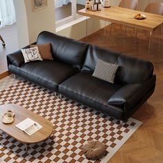 a black leather couch sitting on top of a checkered rug in a living room