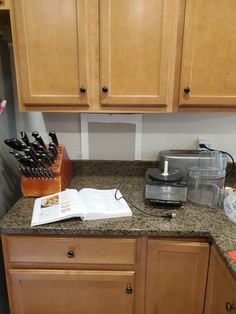 the kitchen counter is covered with knives and cookbooks, along with other utensils