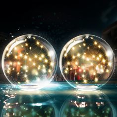 two clear balls with lights floating in the water