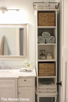 a white bathroom with towels and baskets on the shelves