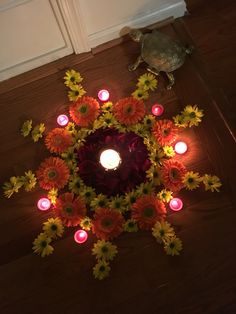 a candle surrounded by flowers and candles on the floor