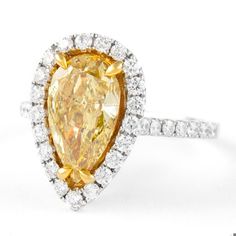 a fancy yellow diamond ring set in white gold with diamonds around the band and an oval cut