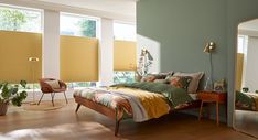 a bed room with a neatly made bed next to two large windows covered in blinds