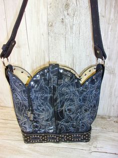 Step into the Wild West with the one-of-a-kind Bucket Bag - a handcrafted beauty that blends cowgirl chic with western sophistication. • Crafted from authentic, recycled cowboy boots.• Western concho accent.• Magnetic closure keeps your essentials secure.• Measures 10"x13" with a leather cross-body strap.• No two alike. Signed and numbered by the artist. This exquisite leather bag is more than just a cowboy boot purse - it's a wearable work of art that celebrates the spirit of the American West. Western Bags With Concho Detail, Western Style Bags With Concho, Western Leather Bags With Concho Details, Western Leather Bags For Rodeo, Western Style Bags For Festivals, Hand Tooled Leather Bags For Rodeo, Best Cowboy Boots, Boot Purse, Totes Boots