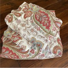 a red and green paisley print pocket square on a wooden floor