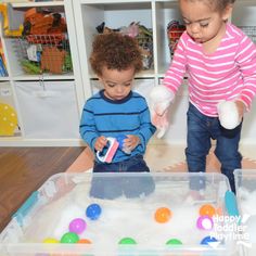 two young children playing with toys in a play room