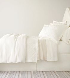 a bed with white sheets and pillows on it