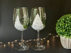 two wine glasses sitting on top of a table next to a potted green plant