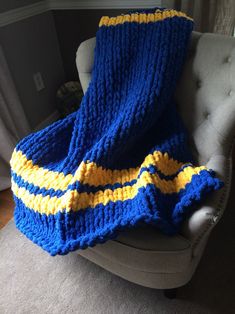 a blue and yellow blanket sitting on top of a chair next to a gray couch