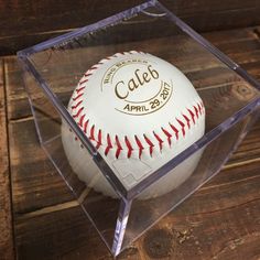 a baseball in a clear case sitting on top of a wooden table