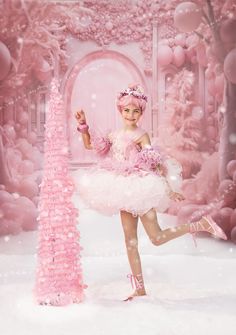 a young ballerina posing in front of a pink christmas tree