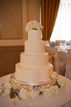 a wedding cake sitting on top of a table next to silver utensils and flowers