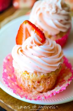 two cupcakes with white frosting sitting on top of a pink and white plate