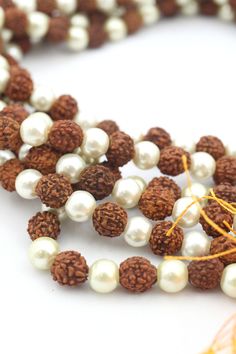 These beautiful beads are made from Rudraksha seeds paired with pearls. Hailing from India, Rudraksha seeds are traditionally used as prayer beads in Hinduism. They are the seeds of the Rudraksha tree, and legend has it that when Lord Shiva awoke from a long meditation, he shed a tear; from this tear grew the Rudraksha tree.Pearls are known as "moti" in Hindi, and they are symbolic of the moon. They encourage positive thinking and balance, and are believed to attract good luck and wealth. Bead S 8mm Pearl Beads Spiritual Necklace, Spiritual Pearl Beaded Necklace With Round Beads, Spiritual Pearl Beaded Necklaces With Round Beads, Traditional Pearl Beads As A Gift, Traditional Pearl Necklace With Gemstone Beads, Traditional Pearl Beads For Gifts, Festive Gift Pearl Necklace With Round Beads, Festival Pearl Necklace With Round Beads, Spiritual Mala With Round Beads For Navratri